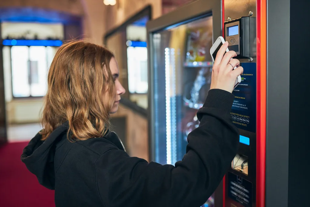 Klient płaci przy automacie vendingowym z wyświetlaczem dotykowym