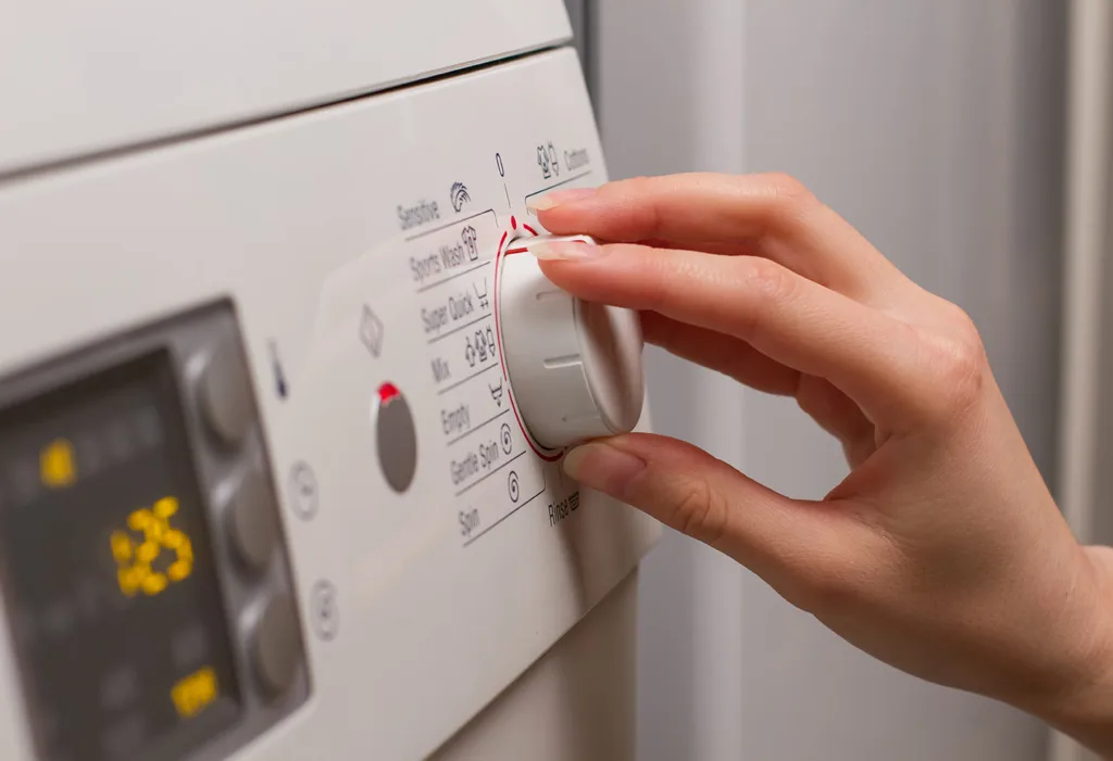 Main tournant le sélecteur de programmes d’un lave-linge équipé d’un écran