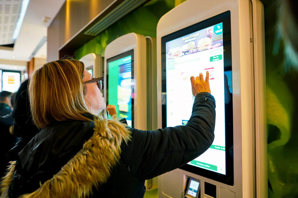 Klient składa zamówienie w dotykowym kiosku samoobsługowym w restauracji